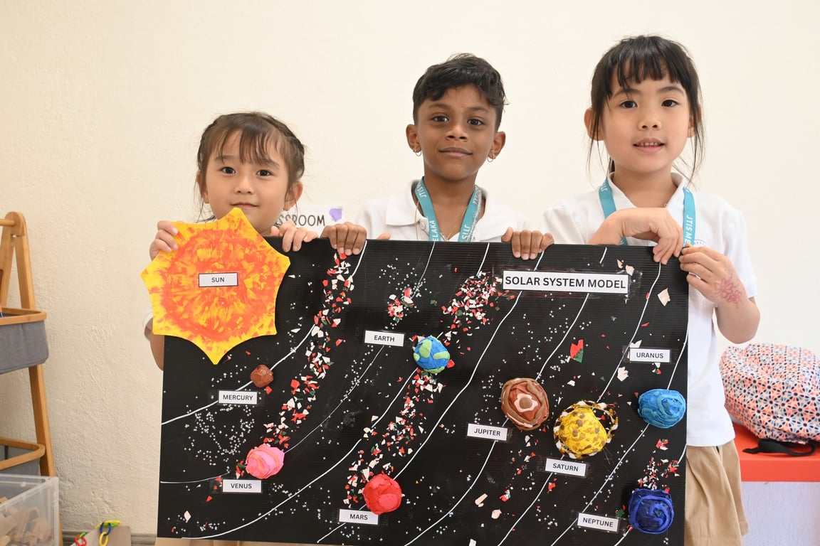 Primary students proudly present their handmade solar system model during a classroom science showcase.