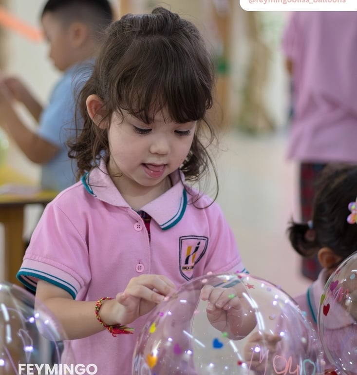 Nursery student decorating a balloon gift for Mother’s Day.