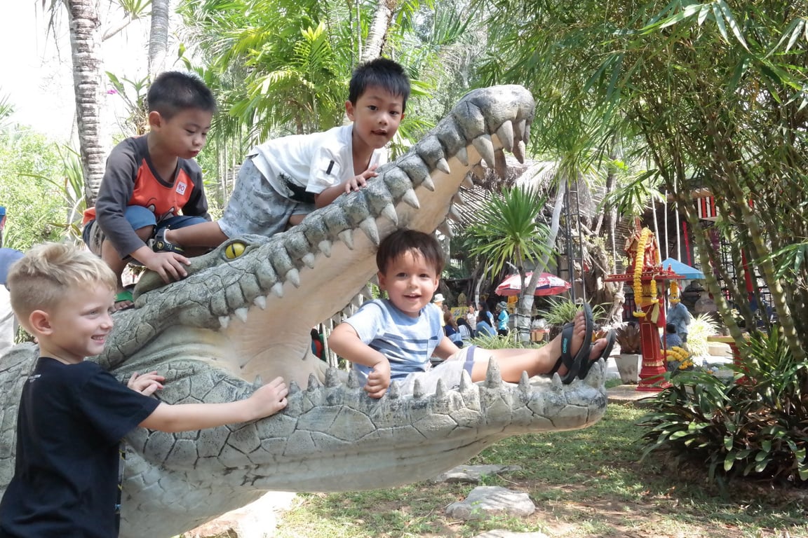 Children's posing on a giant crocodile statue during a school field trip.
