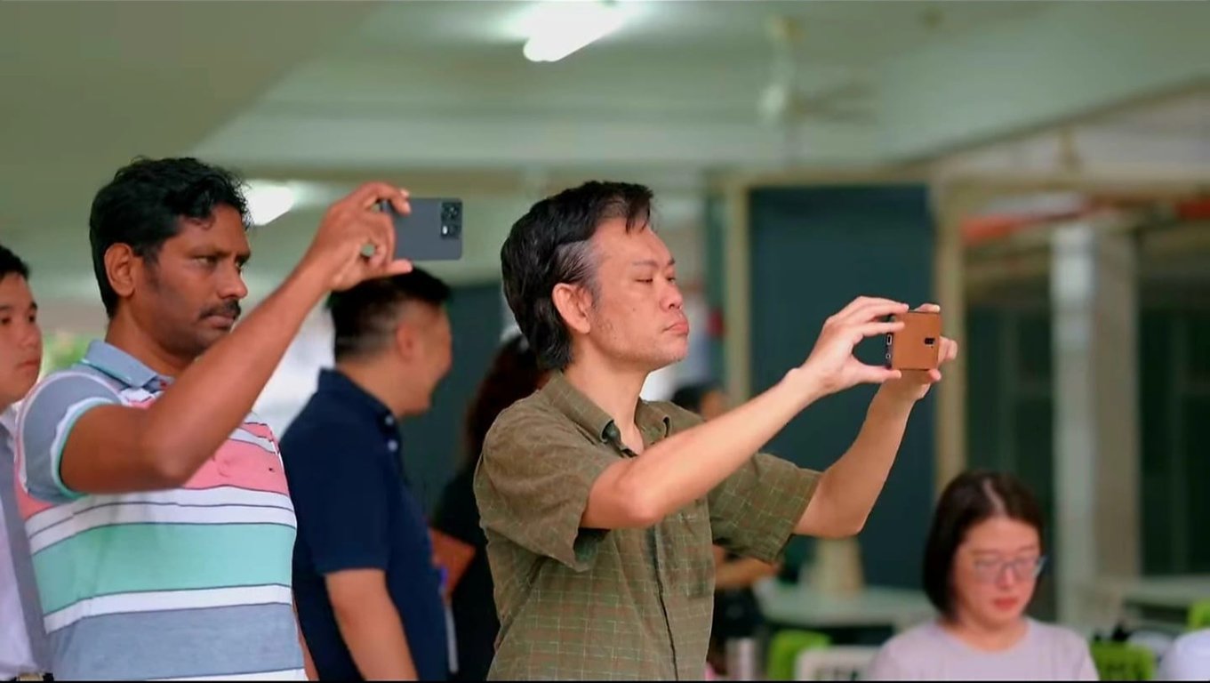 Parents recording a student performance during a school event
