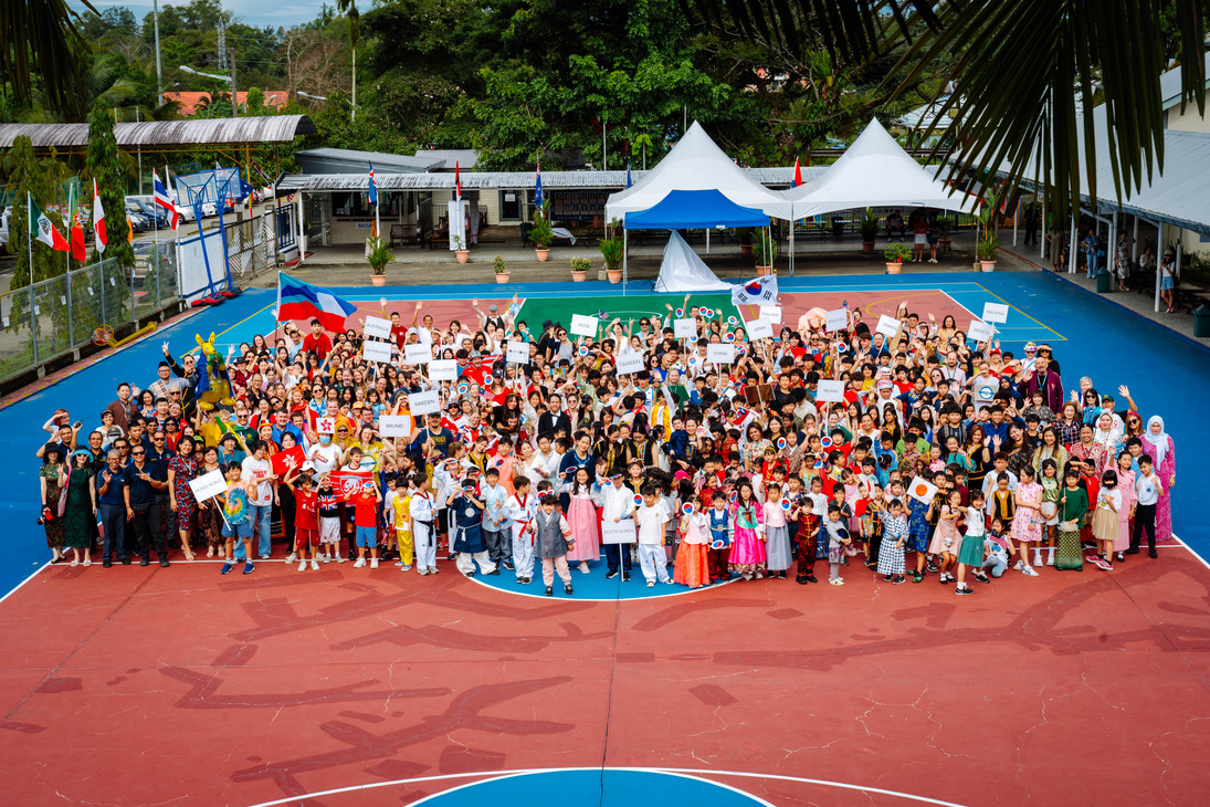 Students, staff, and families gather on the school court for a whole-school photo during KIS International Day celebration.