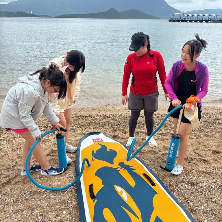 Grade 6 and 7 students preparing paddleboards during water excursion.