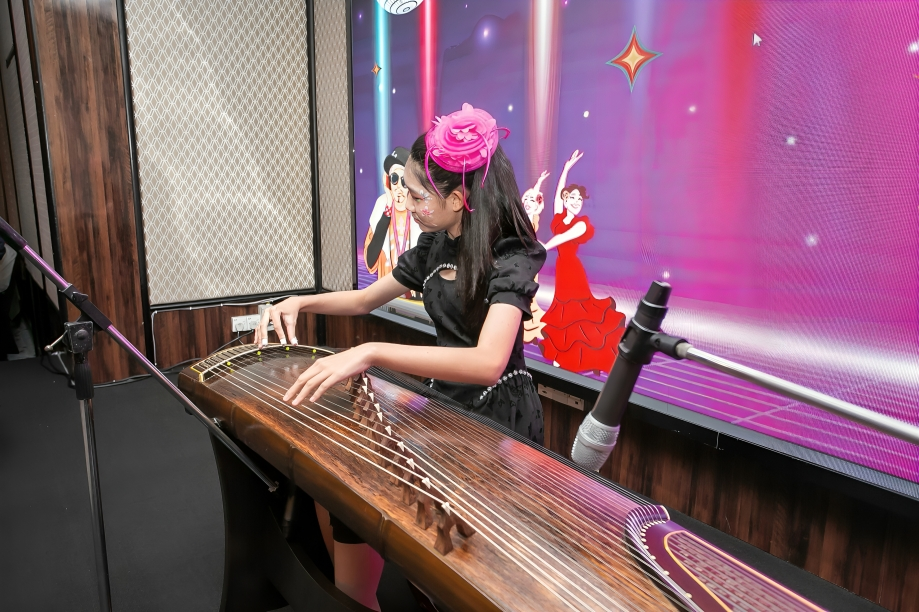 Playing the guzheng during a music performance at school.