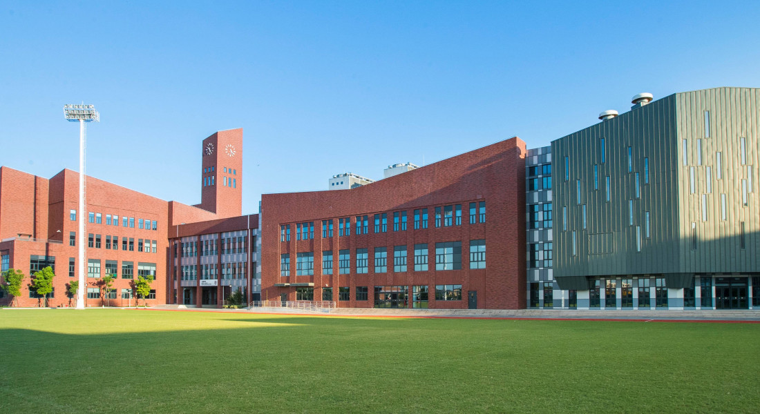 The expansive green playing fields and primary academic buildings.