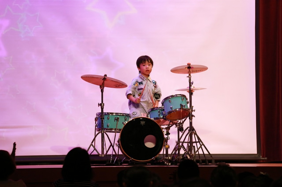 Student performing a drum solo during the school music concert.