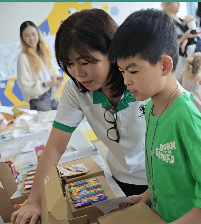 Teacher assisting student at the fundraising booth during Charity Carnival.