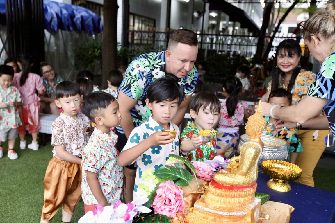 Young children participating in the Songkran water-pouring ceremony, guided by teachers and parents in a moment of respect and tradition.
