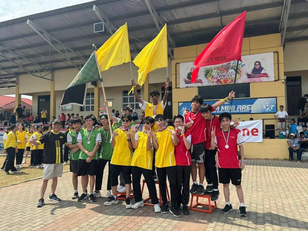Students in house uniforms holding flags and medals after Sports Day events.