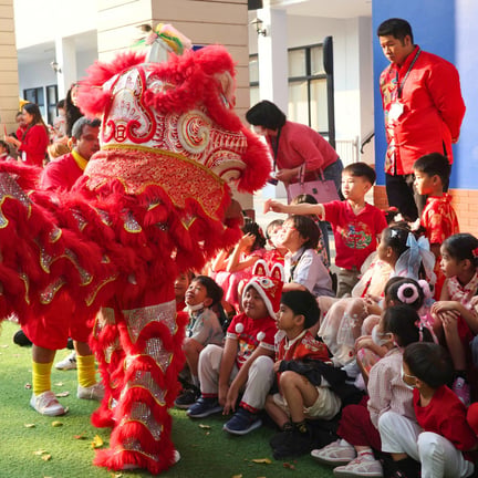 A lively lion dance performance captivates young students seated on the field.