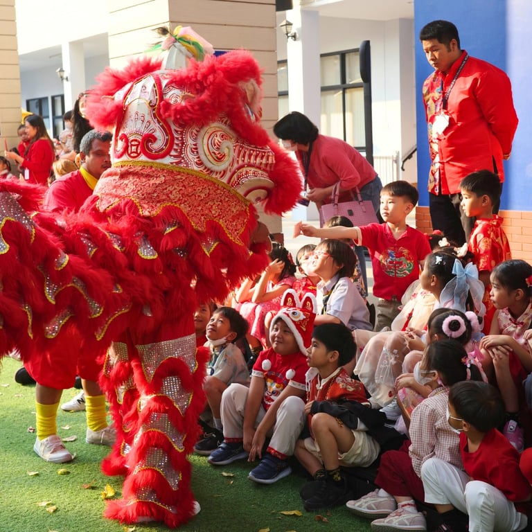 A lively lion dance performance captivates young students seated on the field.