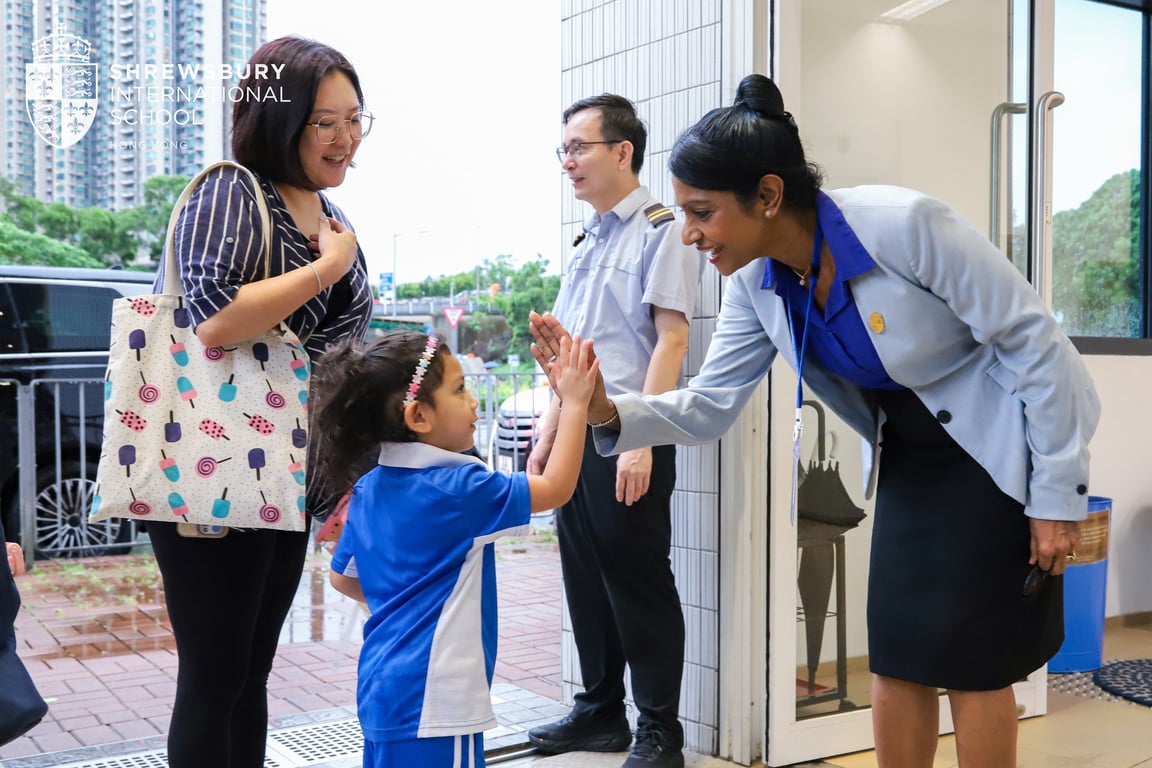 Principal welcoming a student as her parent drops her off.