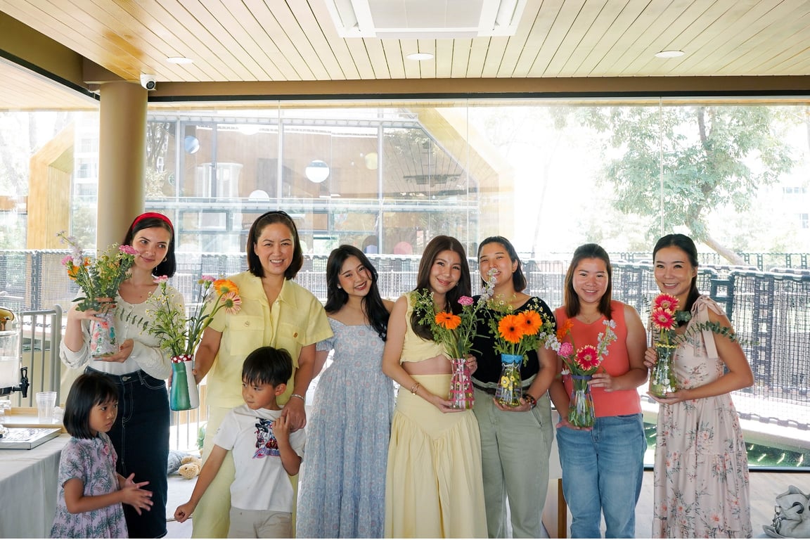 Participants holding their finished flower arrangements during a school art workshop.