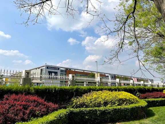 Landscaped gardens and perimeter view of the International School of Beijing campus.