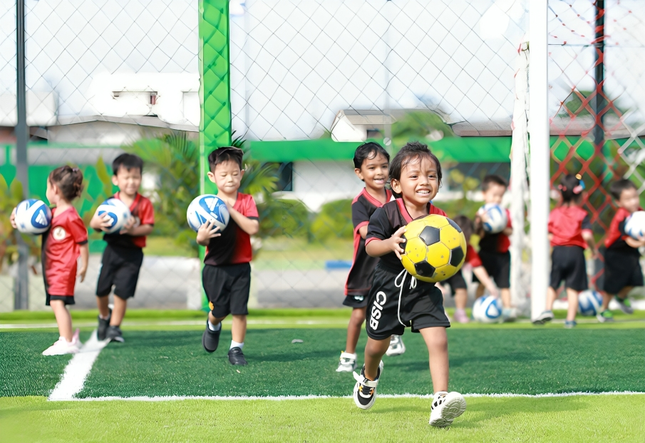 Children practice football skills on the school field.