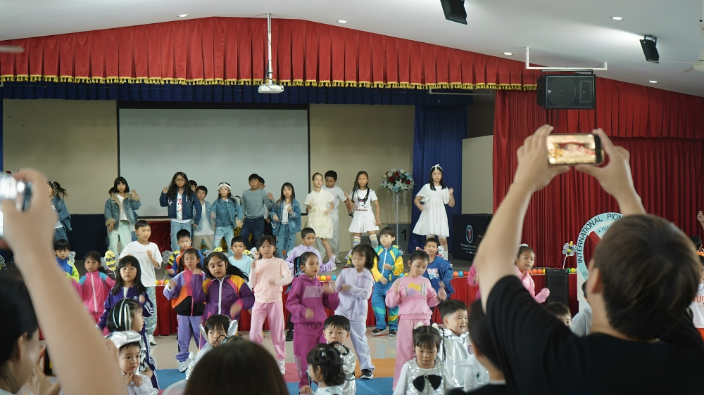 Primary students perform a group dance on stage.