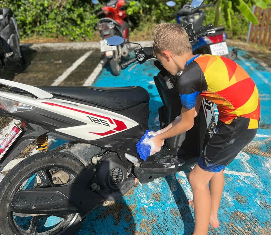 Year 3 learner helping clean a scooter at charity car wash.
