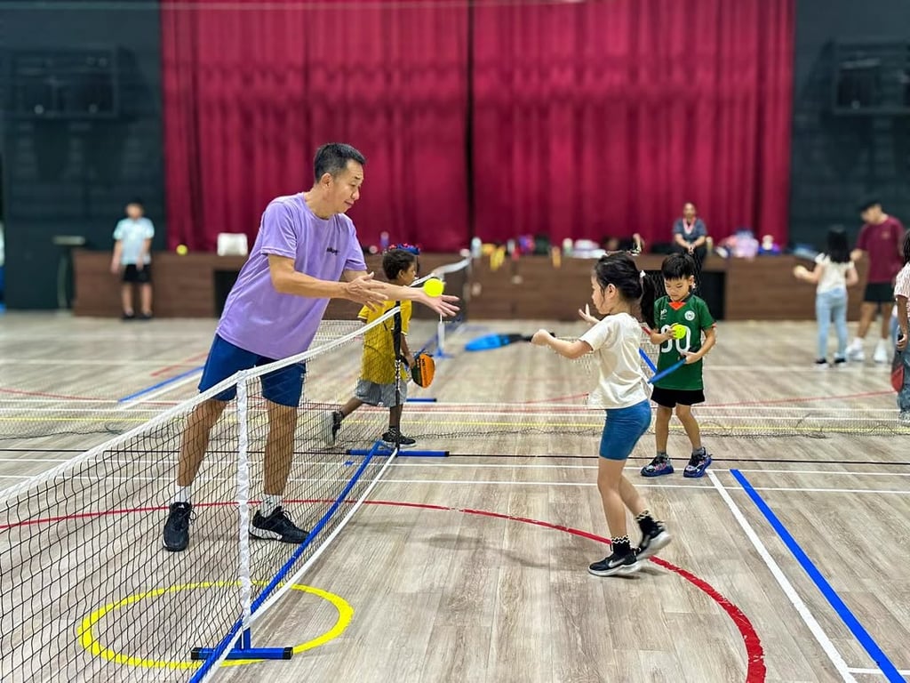 A coach teaching children how to play pickleball.