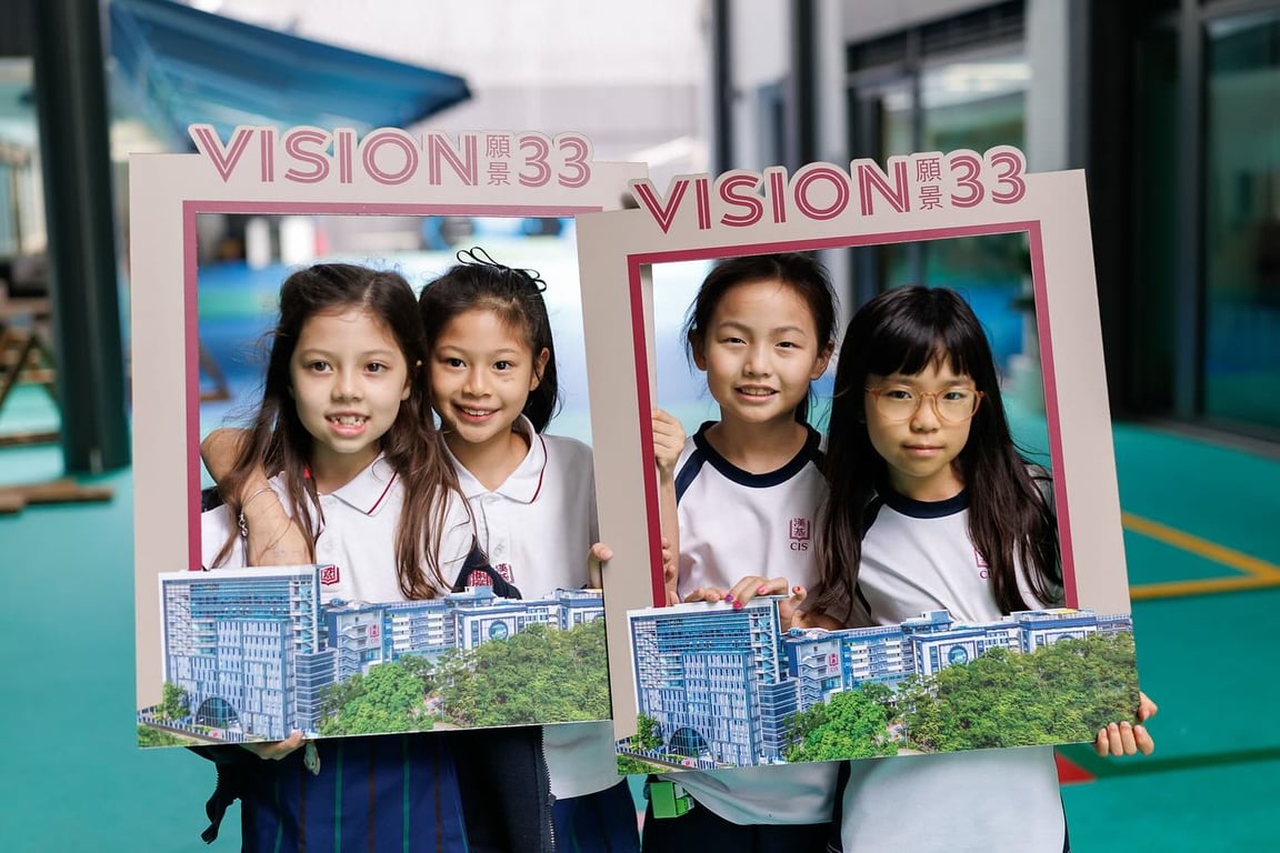Primary students holding Vision ’33 photo frames on campus.
