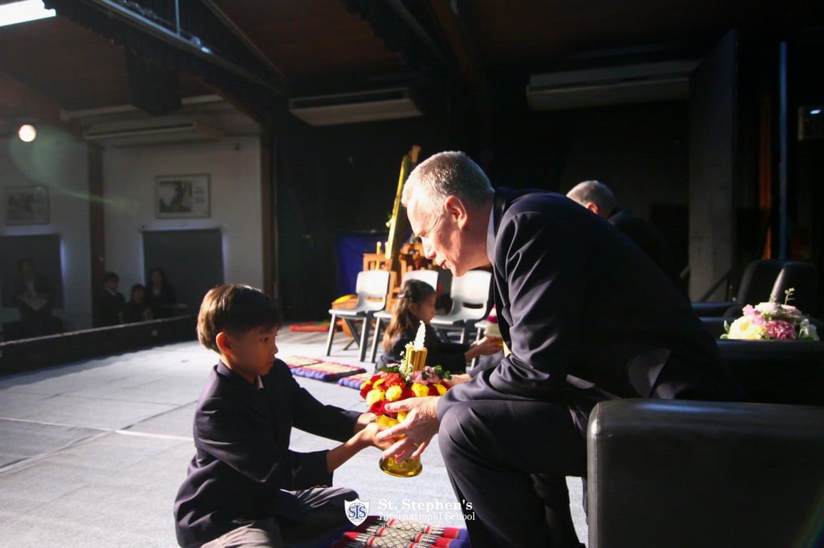 Student presenting a flower tray during the Wai Kru ceremony.