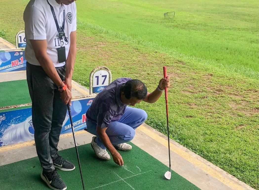 A student receives one-on-one instruction during a practical golf session.