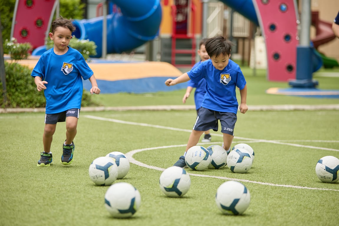 Early Years students practicing ball control during football class.