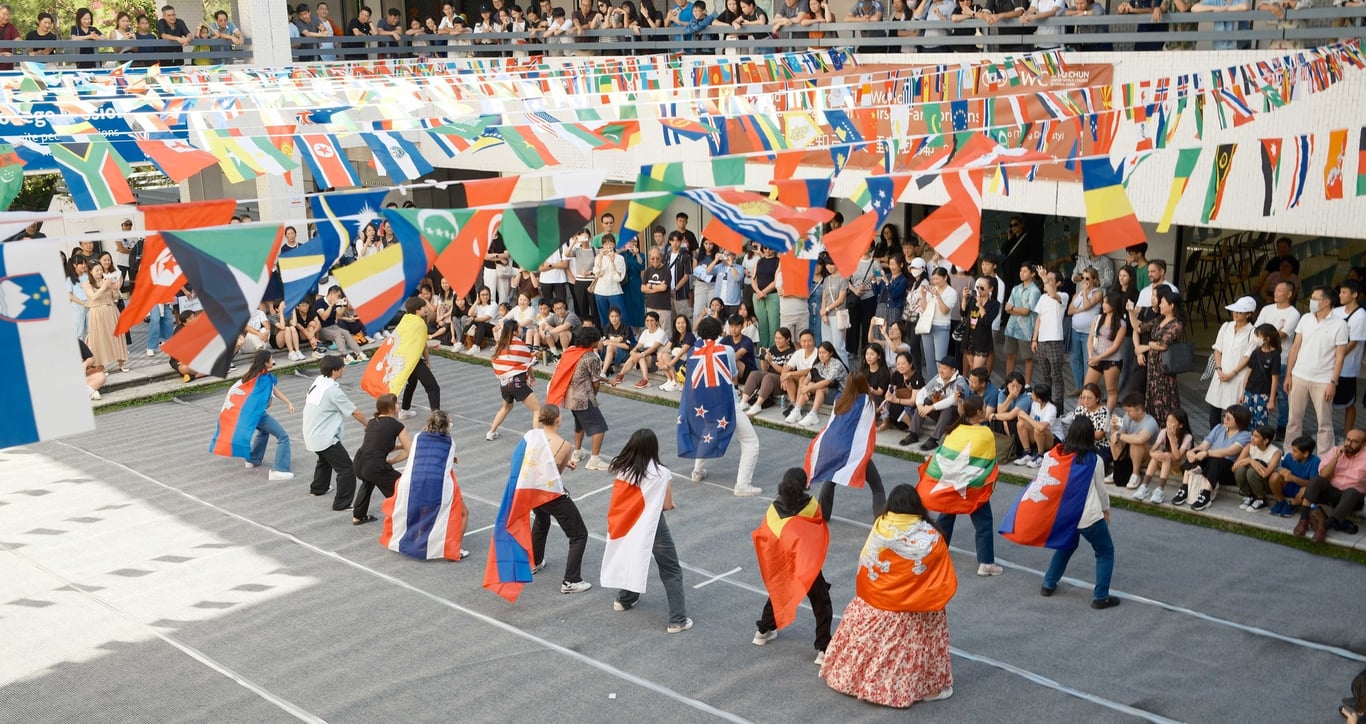 Students celebrate Cultural Day with a lively outdoor event, waving flags from around the world.