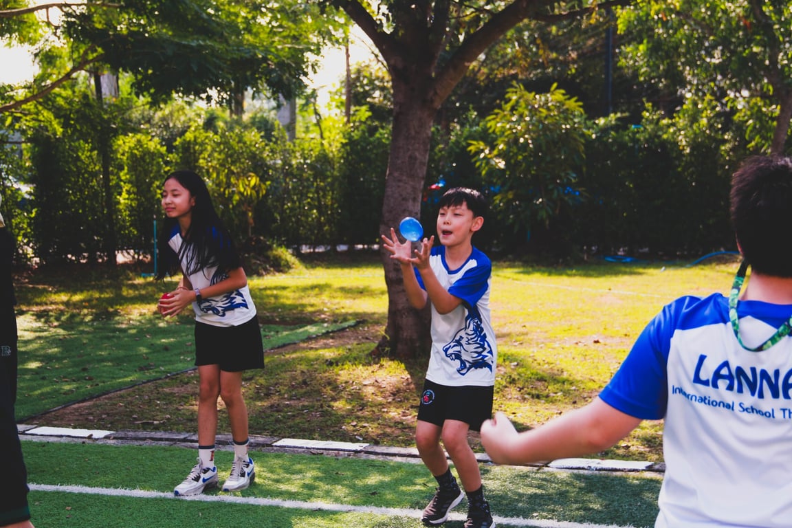Primary students playing catch with water balloons on Sports Day 2025.