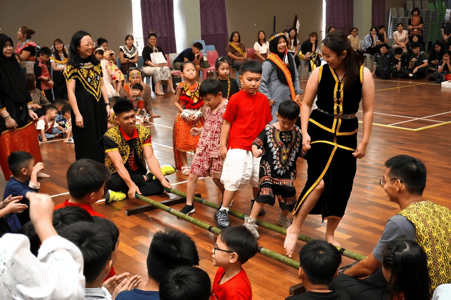 Students try traditional bamboo dance during Woodlands’ vibrant Cultural Day celebration.