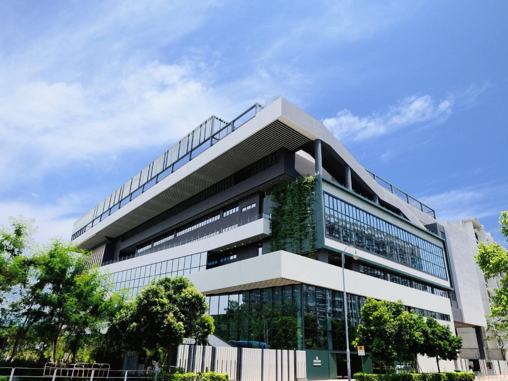 The modern Malvern College Hong Kong campus building surrounded by greenery under a bright sky.