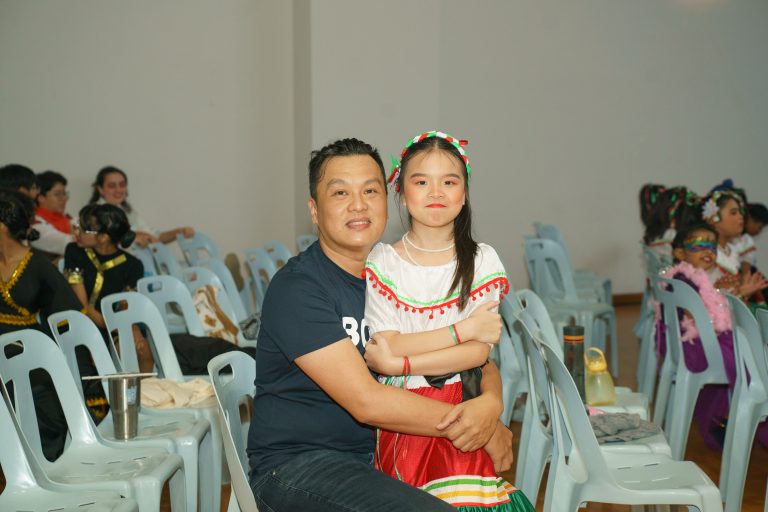 Student in festive costume sitting with parent before the performance.