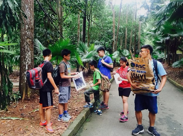 A group of students participates in an educational scavenger hunt at a forest reserve.