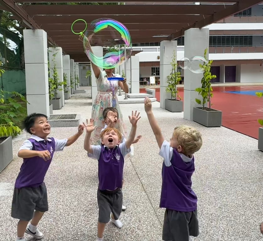 Early Years students play with bubbles.