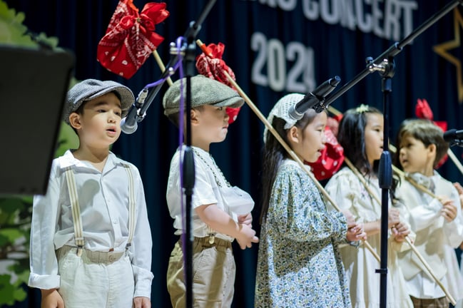 Young students performing on stage in themed costumes during a school concert, showcasing confidence, teamwork, and creativity.