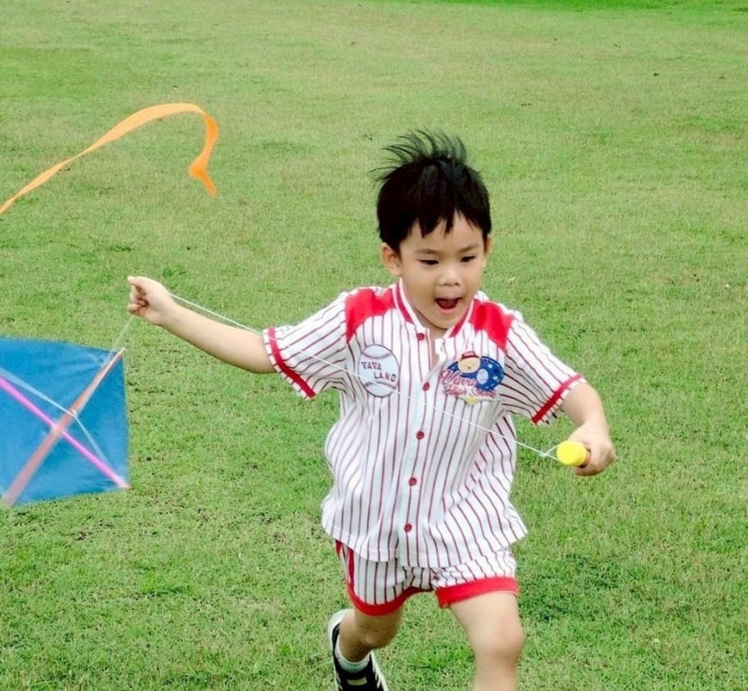Summer camp student flying a handmade kite outdoors.