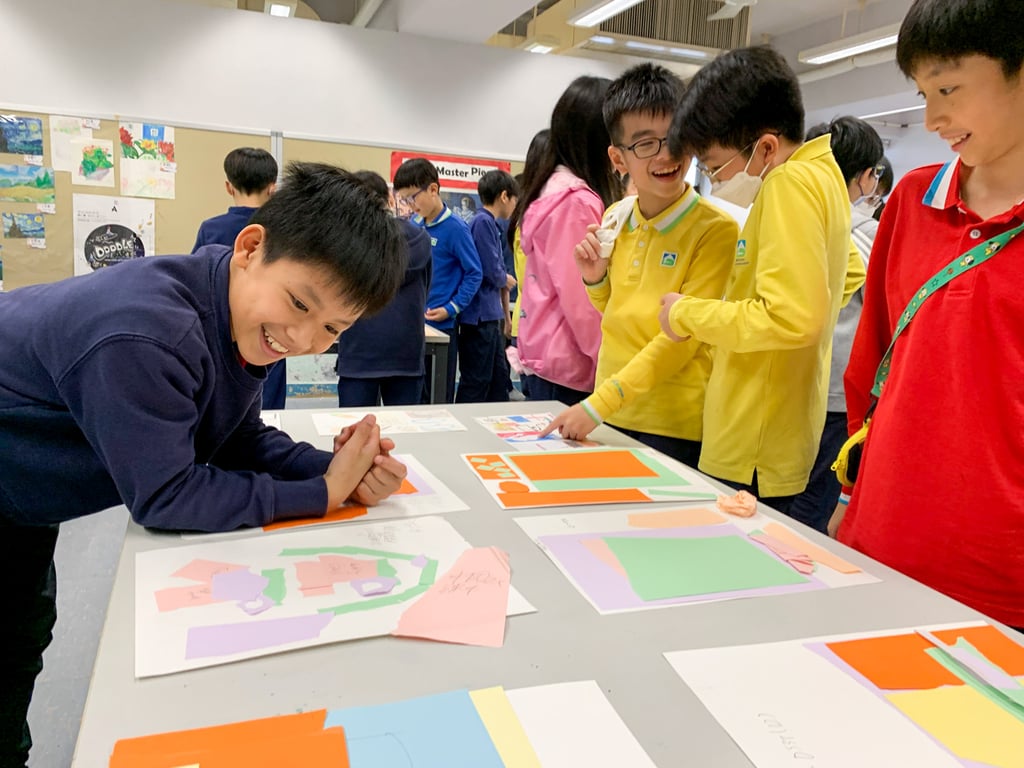 Students presenting paper designs in a classroom art project.