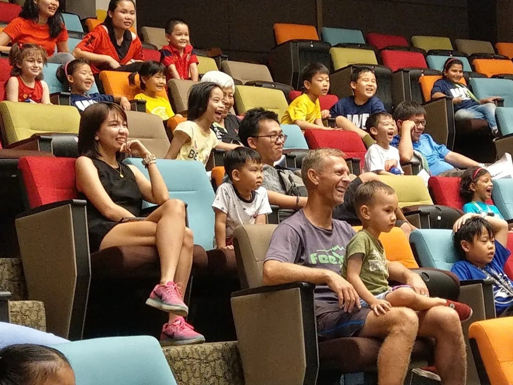 Parents and children enjoying a student performance together in the school auditorium