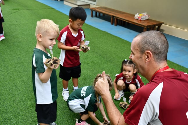 Kindergarten students learning to plant seeds during an outdoor activity.