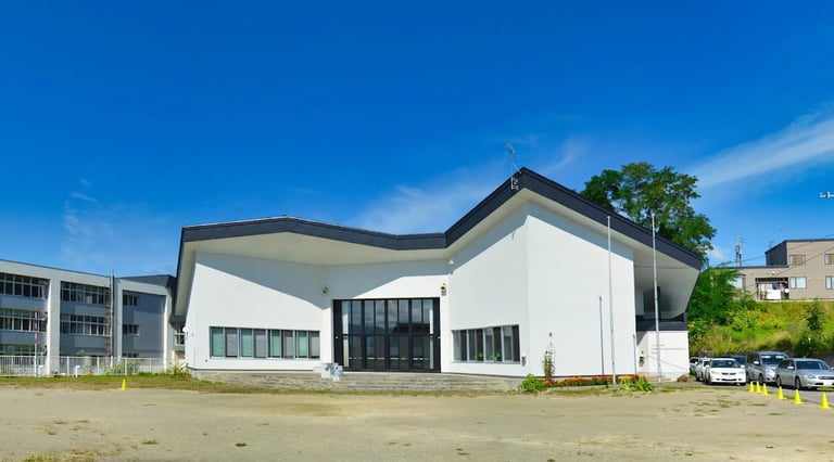 An exterior view of the Niseko campus building under a clear blue sky.