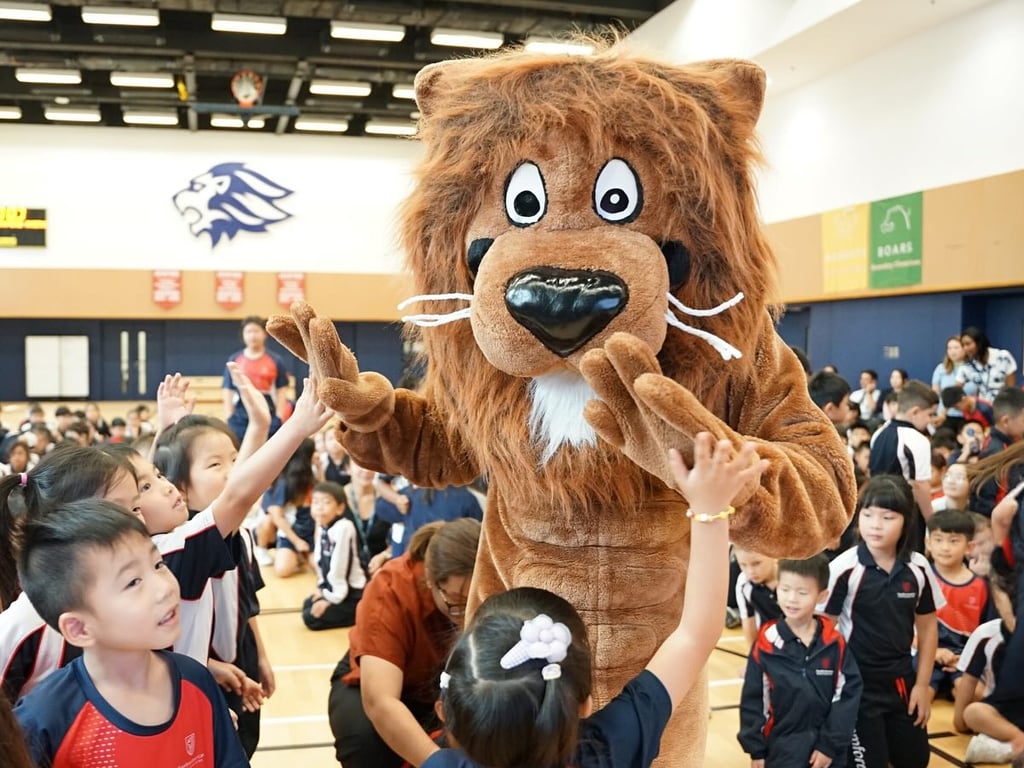 Young learners high-fiving the Stamford Lion at school event.