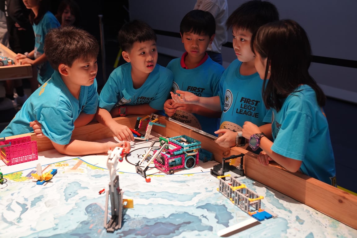 Elementary students programming LEGO robots in a team challenge.