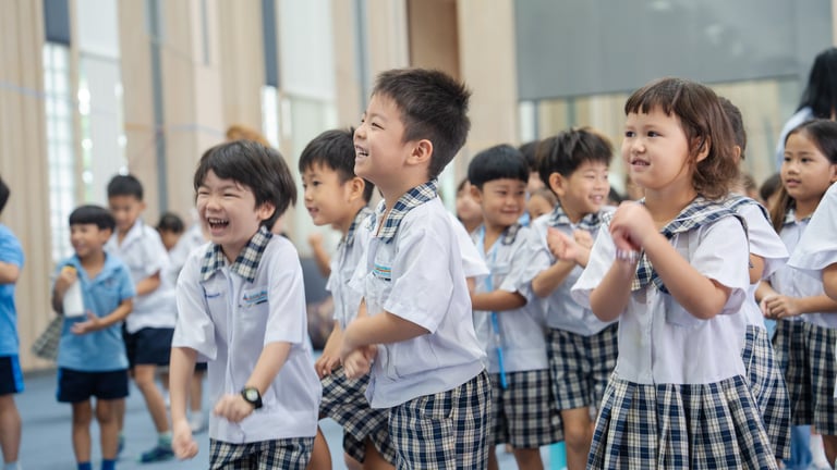 Young students laughing and clapping together during a fun activity.