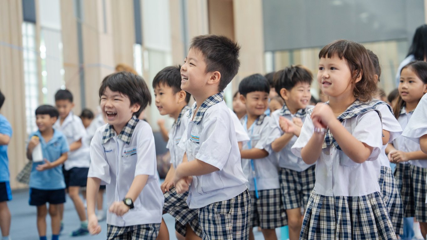 Young students laughing and clapping together during a fun activity.