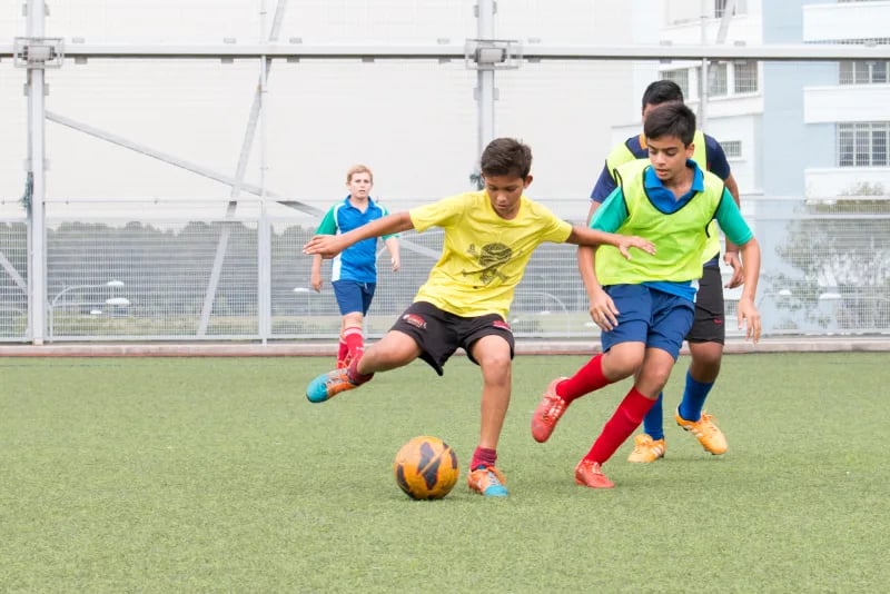 Students playing football on the sports pitch on campus