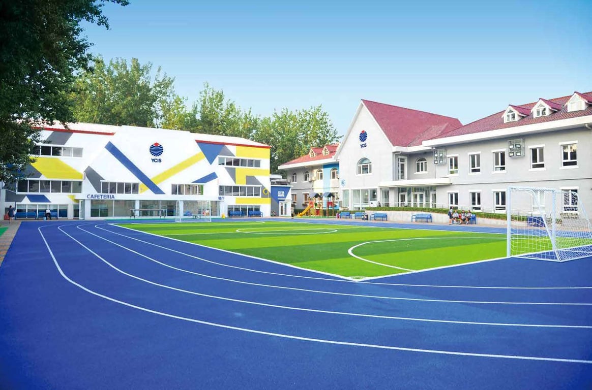 Modern school buildings and play areas surrounding the primary sports field.