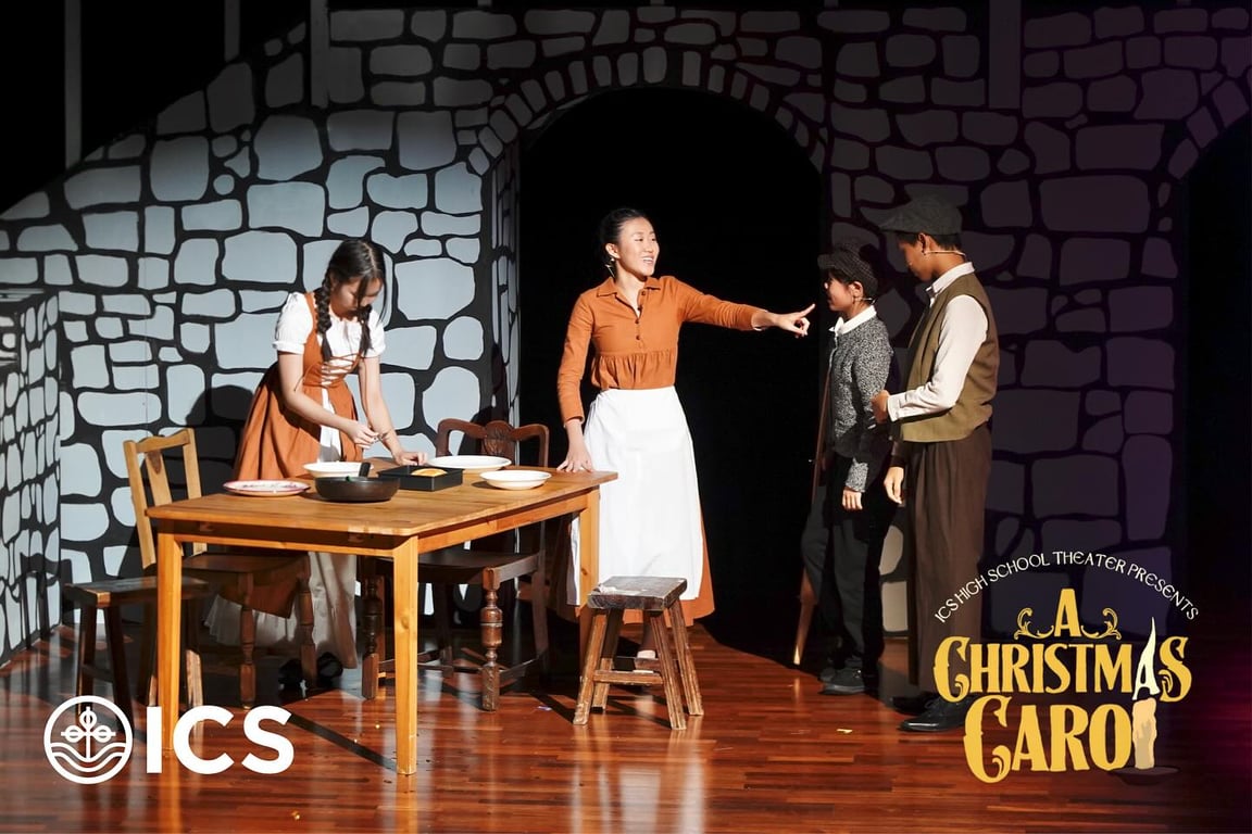 High school students performing A Christmas Carol on the ICS theater stage.
