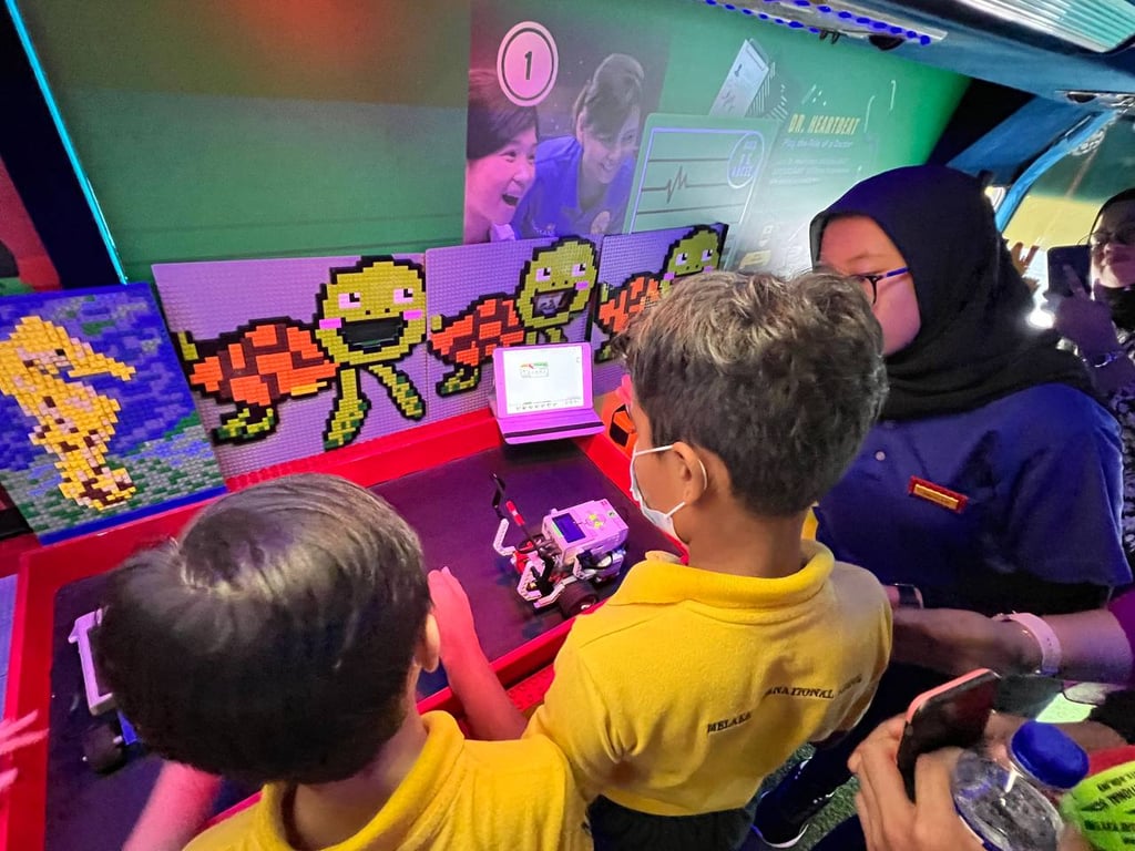 Students interact with robotics and pixel art at a mobile STEM exhibition, exploring technology through hands-on activities.