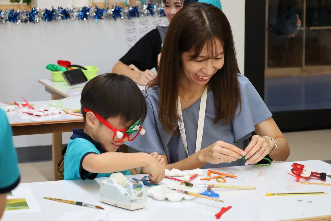 Year 1 student and parent crafting festive photo holder ornaments together.