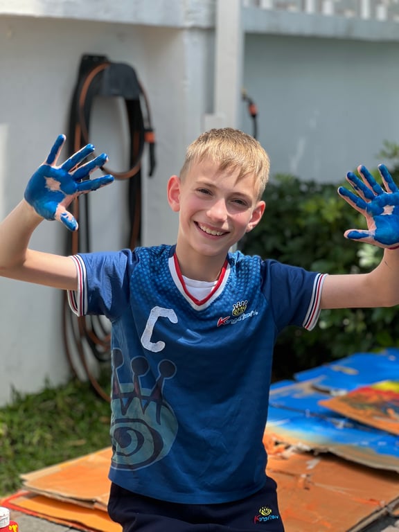 Year 6 Student showing painted hands during outdoor art activity.