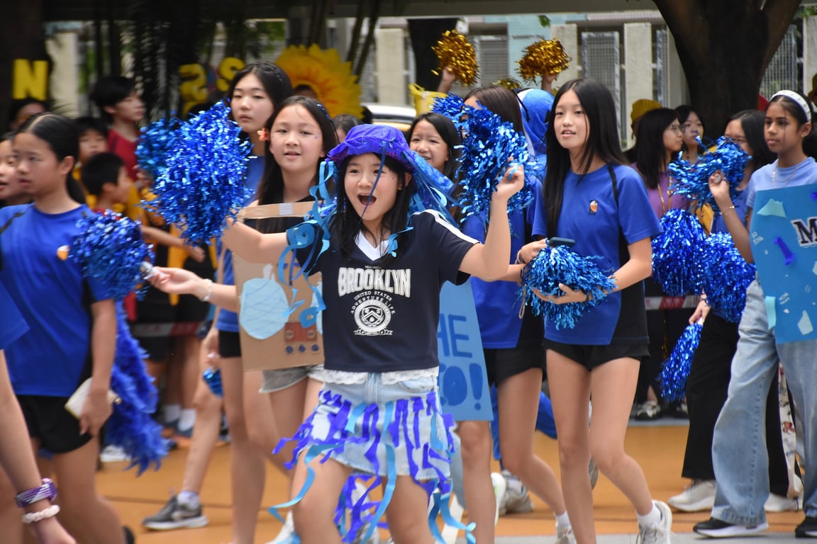 Students marching with blue pom-poms during a school spirit event.