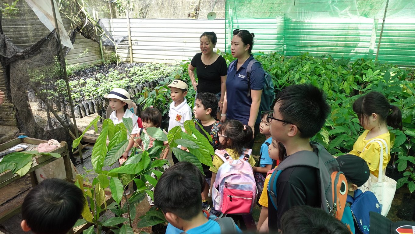 Early years and primary students learn about sustainable planting during a greenhouse visit.